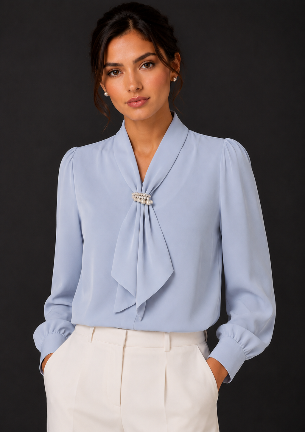 Woman wearing a light blue blouse with a tie detail against a black background