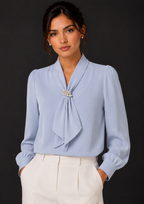Woman wearing a light blue blouse with a tie detail against a black background