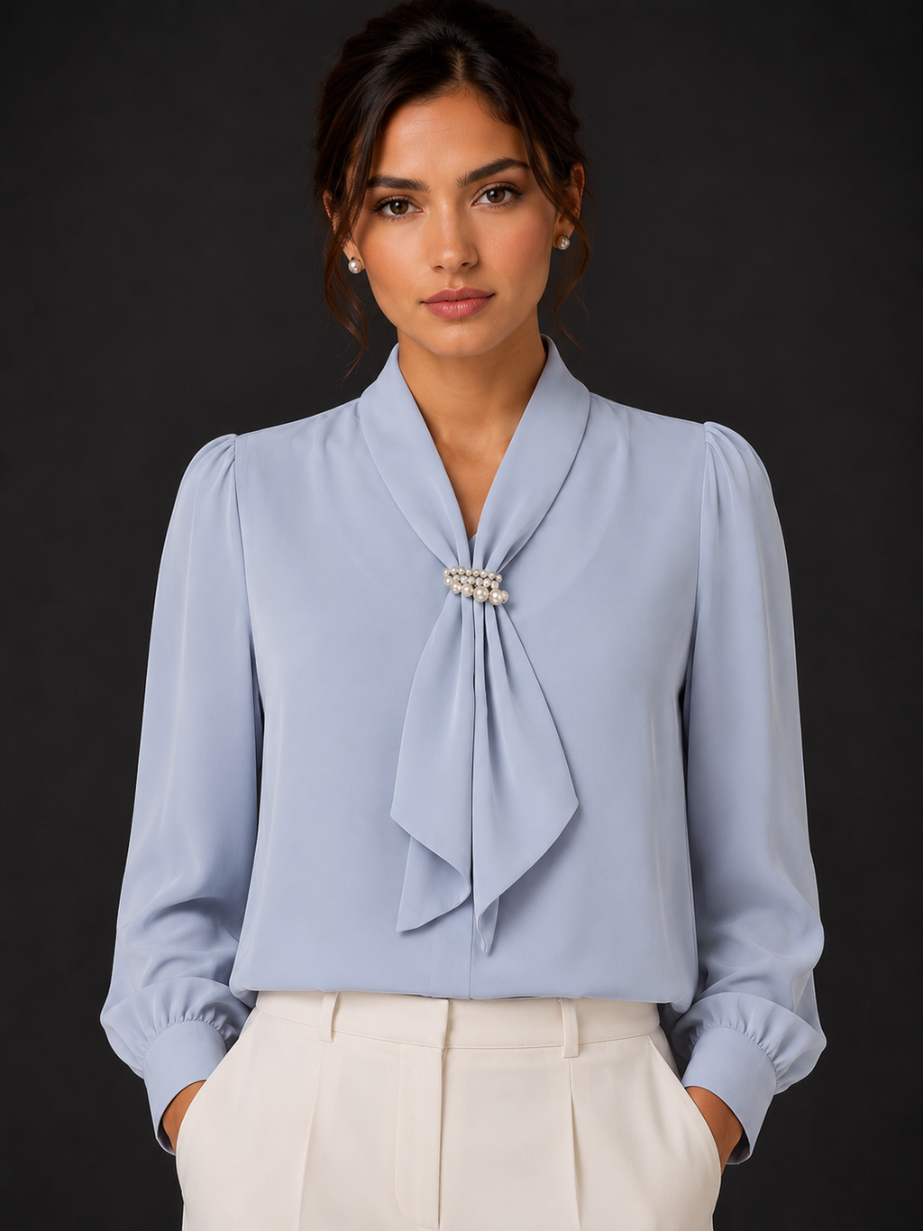Woman wearing a light blue blouse with a tie detail against a dark background