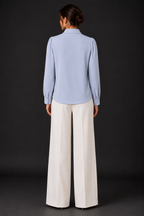 Person wearing a light blue shirt and white pants on a black background