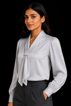 Woman wearing a light gray blouse with a tie detail against a black background