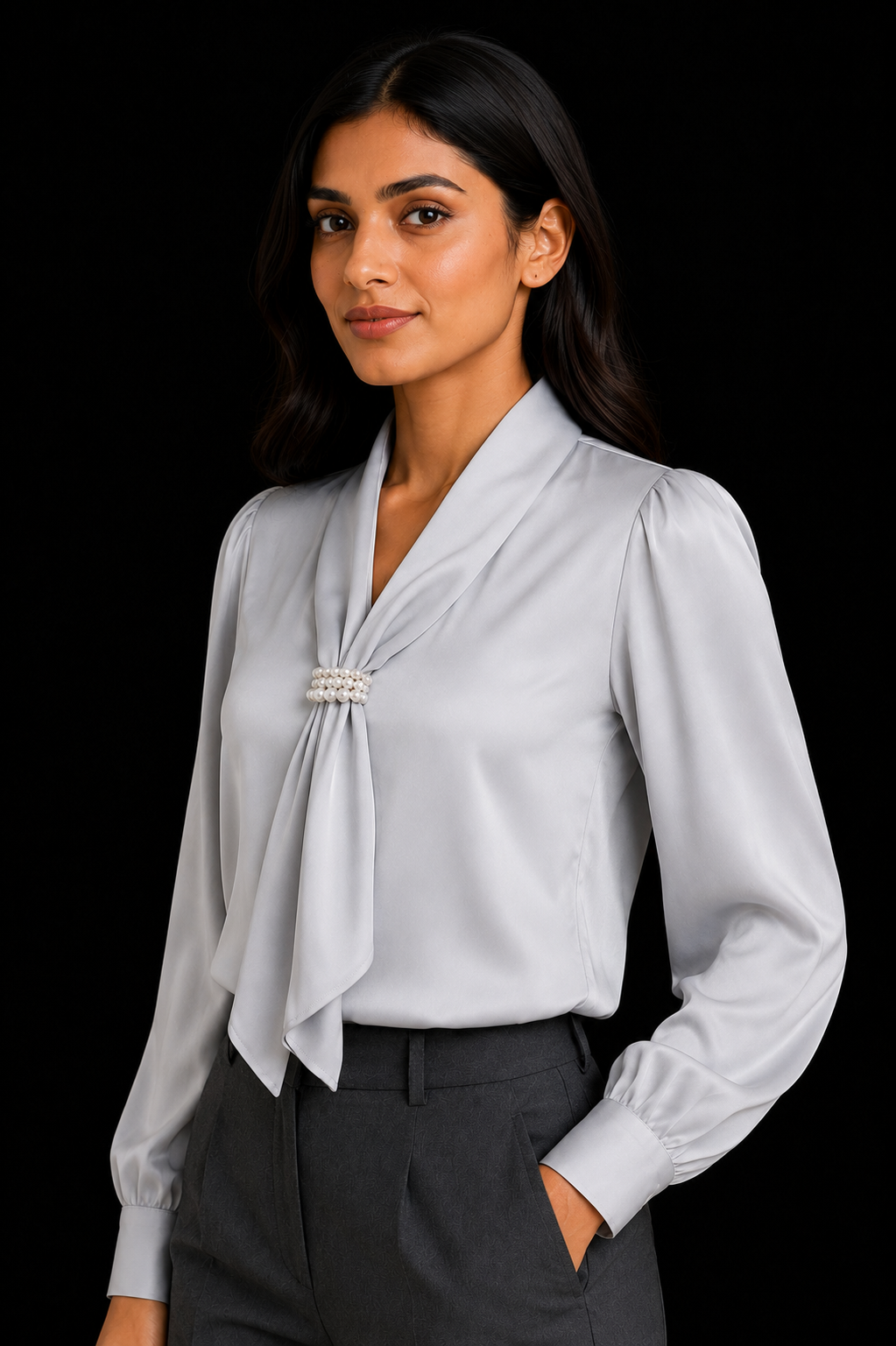 Woman wearing a light gray blouse with a tie detail against a black background