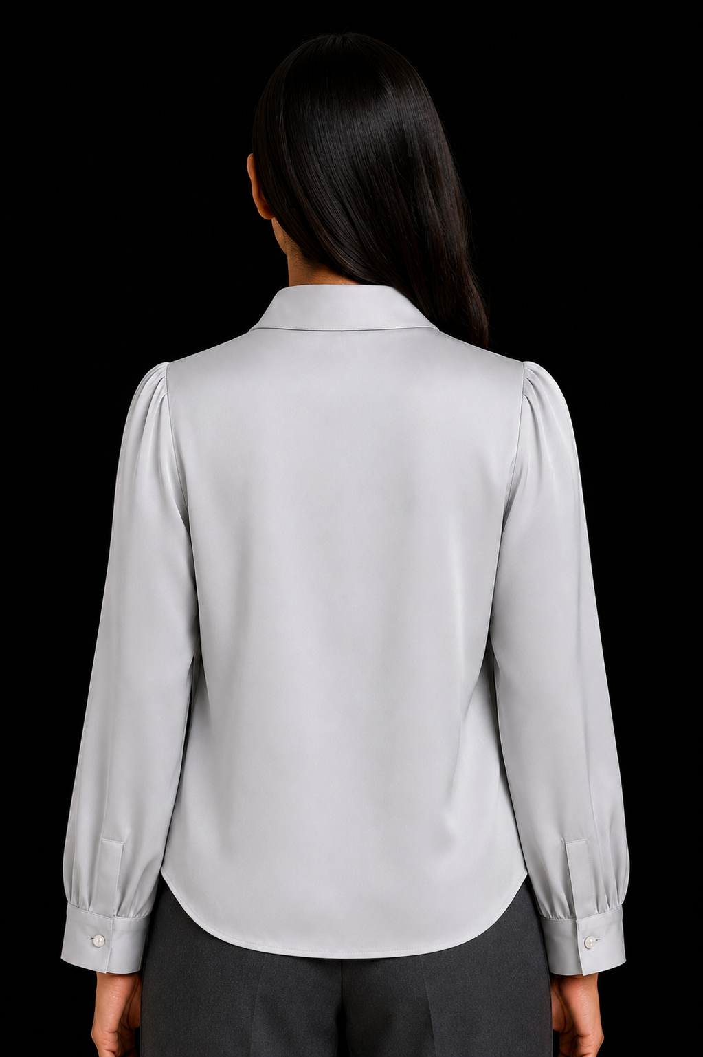 Person wearing a light gray blouse with long sleeves on a black background