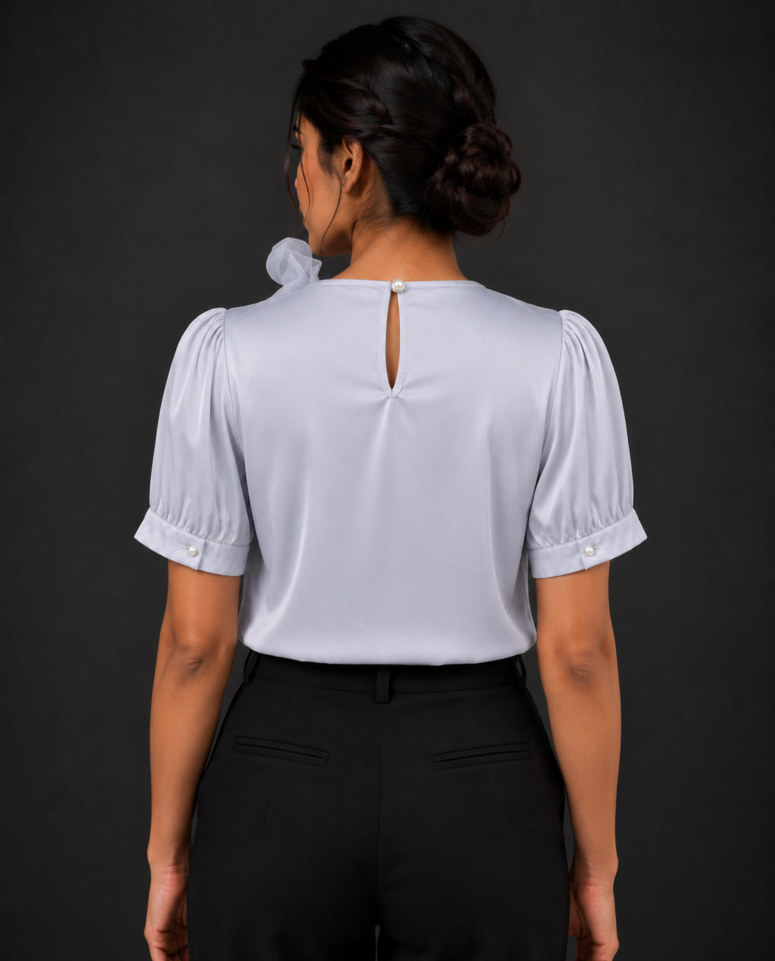 Person wearing a light blue blouse with puffed sleeves against a dark background