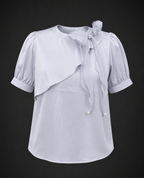 Light blue blouse with ruffled sleeves and a bow on a black background
