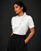 Woman wearing a white blouse with ruffled details against a black background