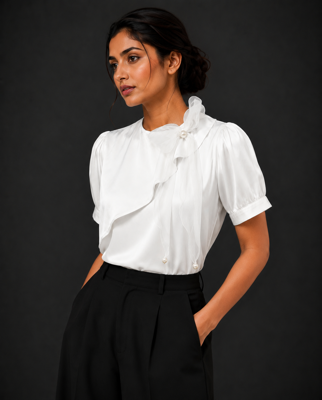 Woman wearing a white blouse with ruffled details against a black background