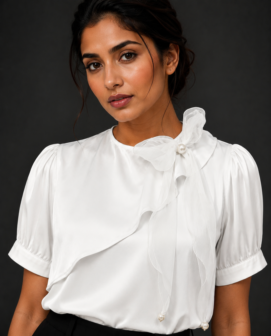 Woman wearing a white blouse with ruffled details against a black background