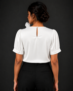 Person wearing a white blouse with puffed sleeves against a black background