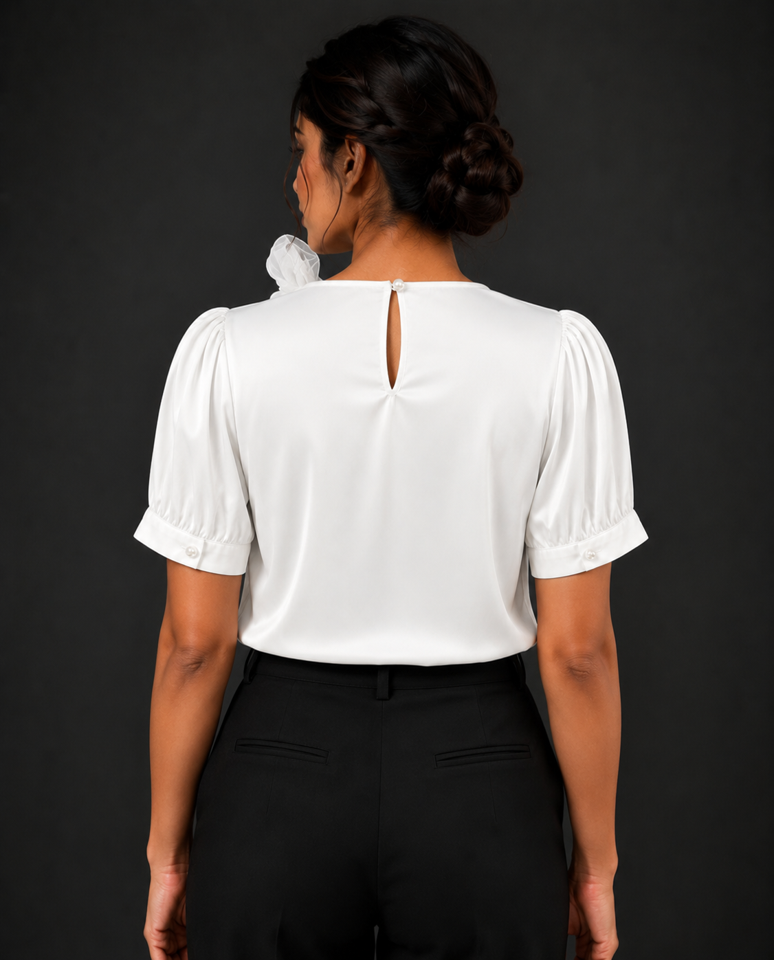 Person wearing a white blouse with puffed sleeves against a black background