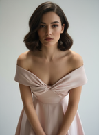 Woman wearing a light pink off-shoulder dress against a plain background