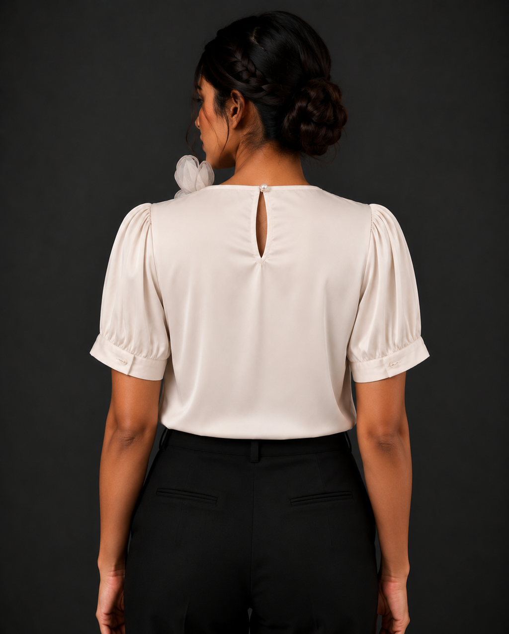 Person wearing a white blouse with puffed sleeves against a black background