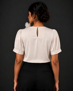 Person wearing a white blouse with puffed sleeves against a black background