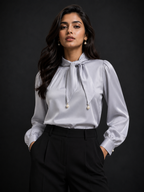 Woman wearing a light gray blouse with a bow detail against a black background