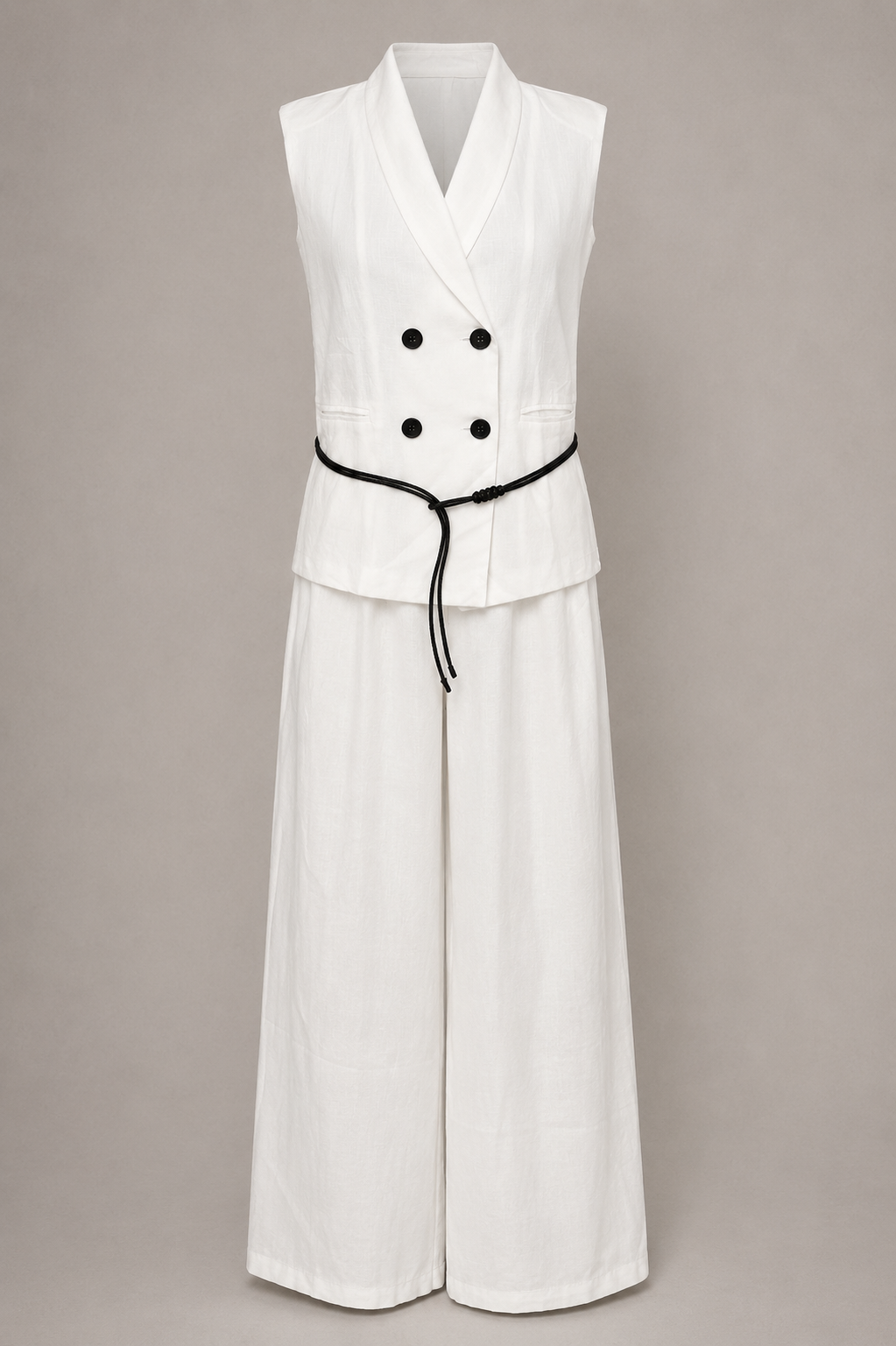 White sleeveless jumpsuit with black buttons and belt on a beige background