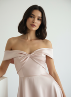 Woman wearing a light pink off-shoulder dress against a white background