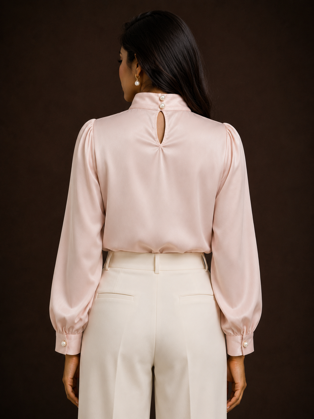 Woman wearing a light pink blouse with a cutout back design on a dark background