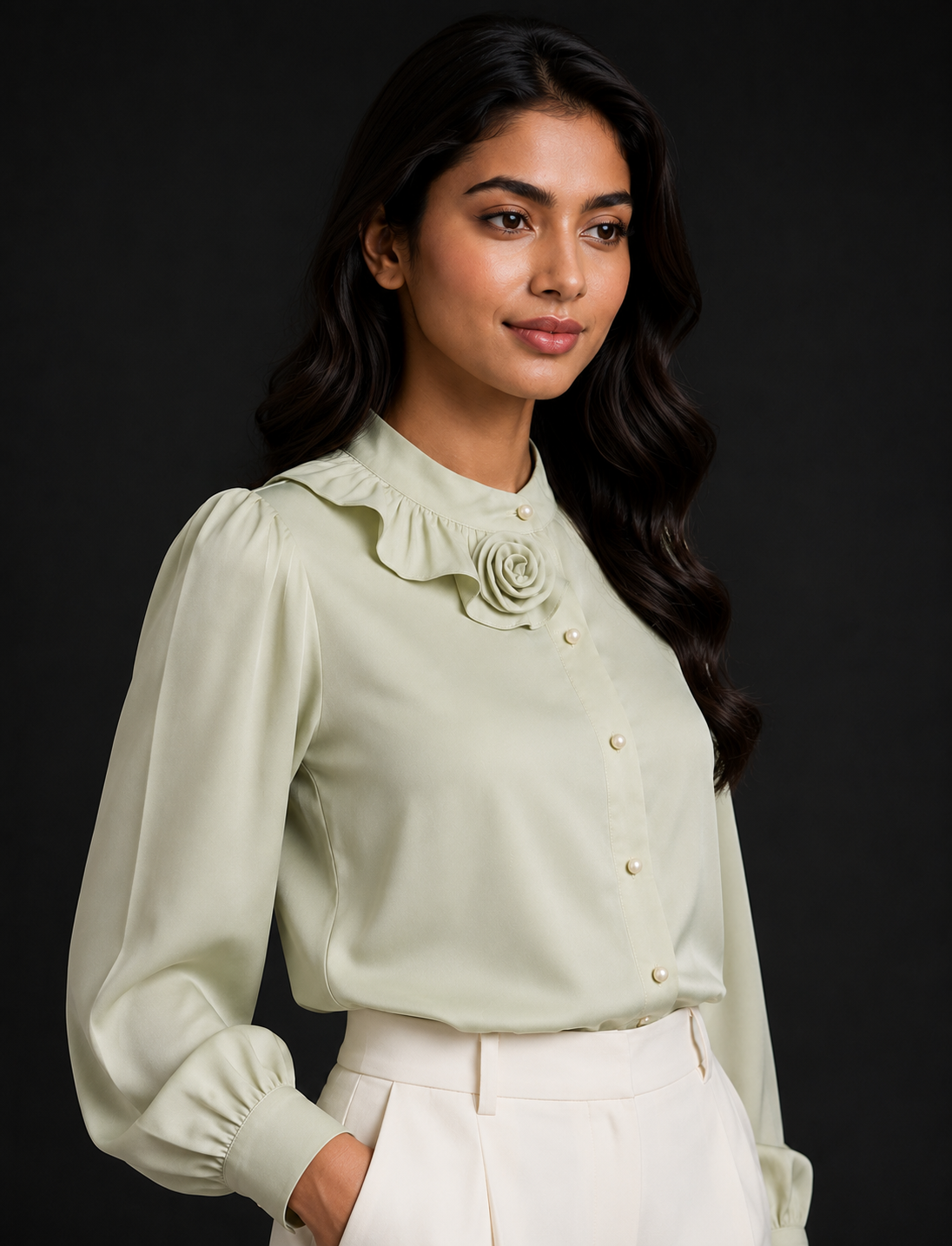 Woman wearing a light green blouse with a floral detail on a black background