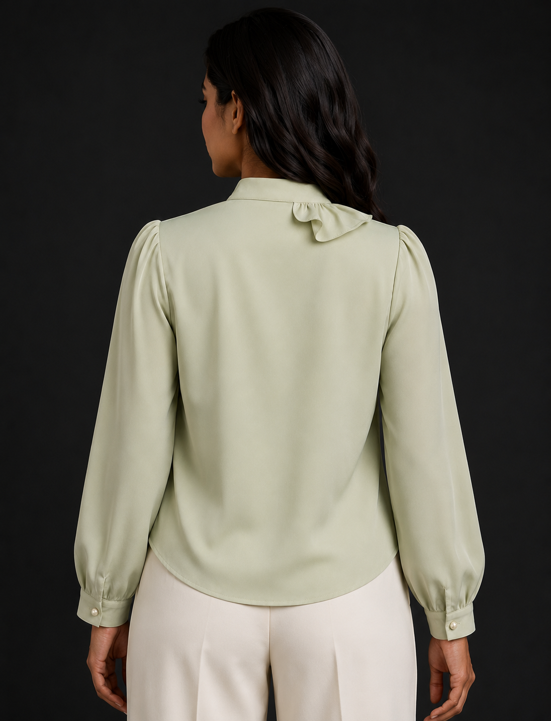 Woman wearing a light green blouse with long sleeves and a dark background
