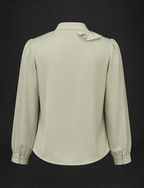 Light green blouse with long sleeves and a bow detail on a black background