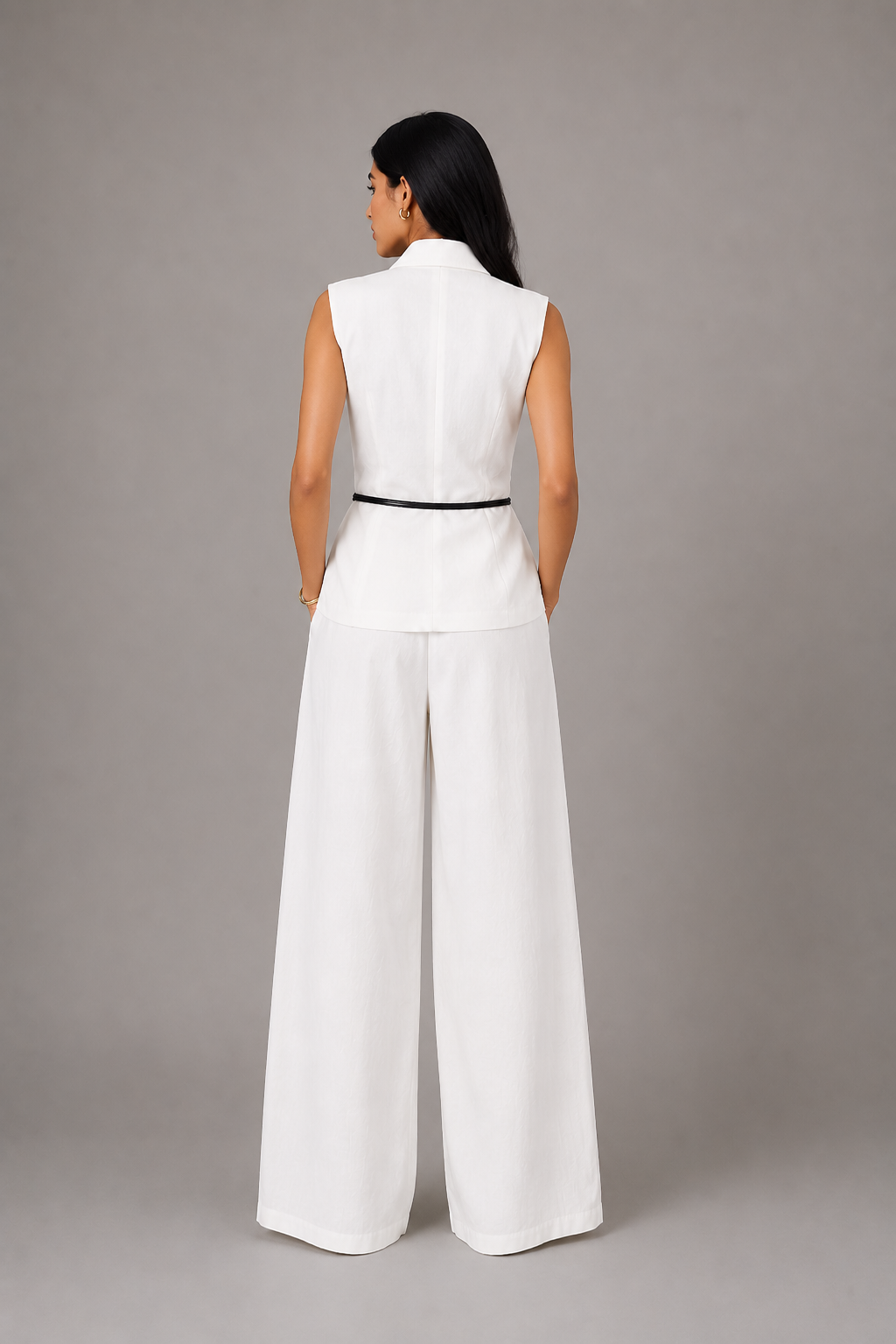 Woman wearing a white sleeveless top and wide-leg pants against a gray background