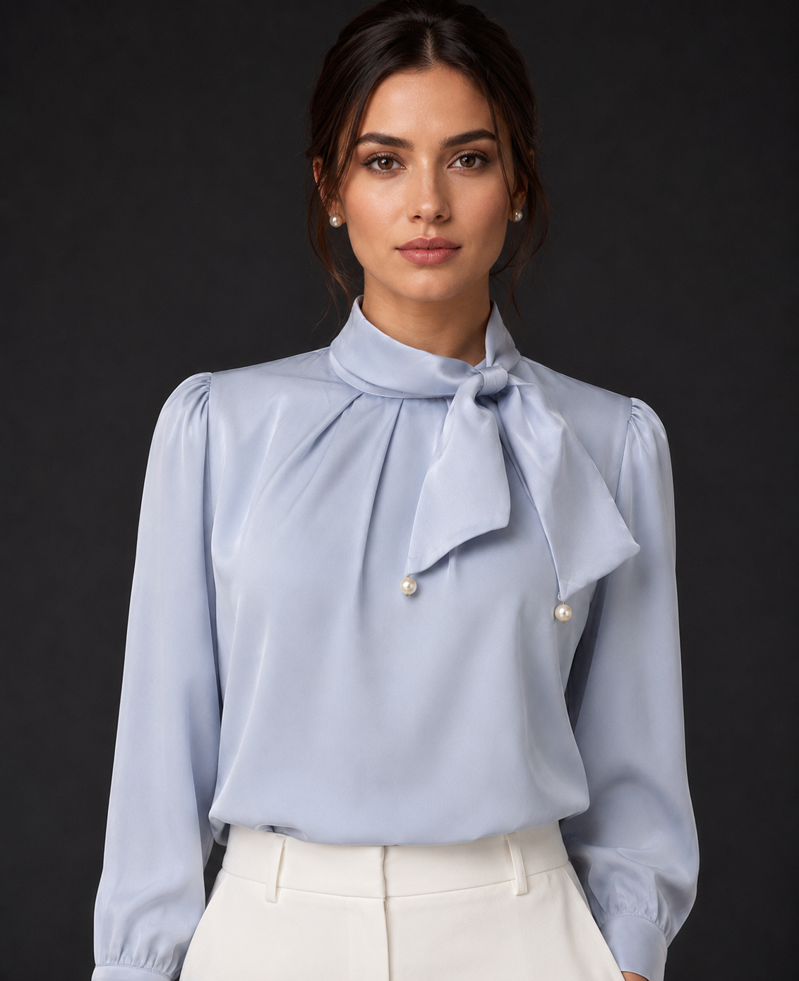 Woman wearing a light blue blouse with a bow tie against a dark background