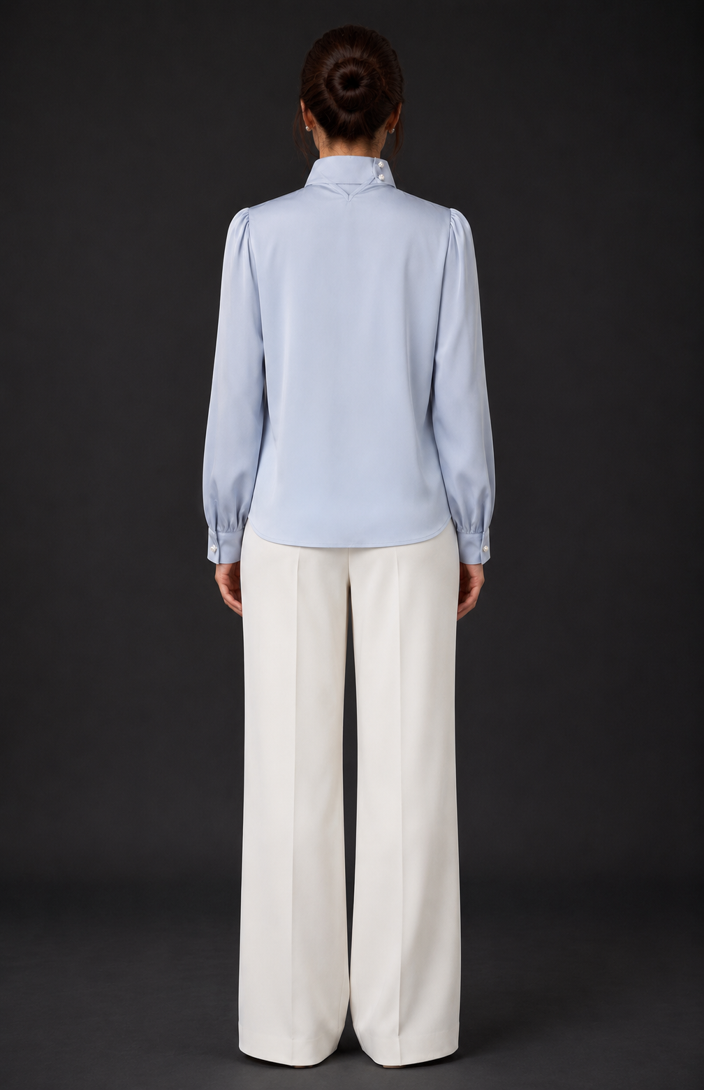 Person wearing a light blue shirt and white pants against a black background