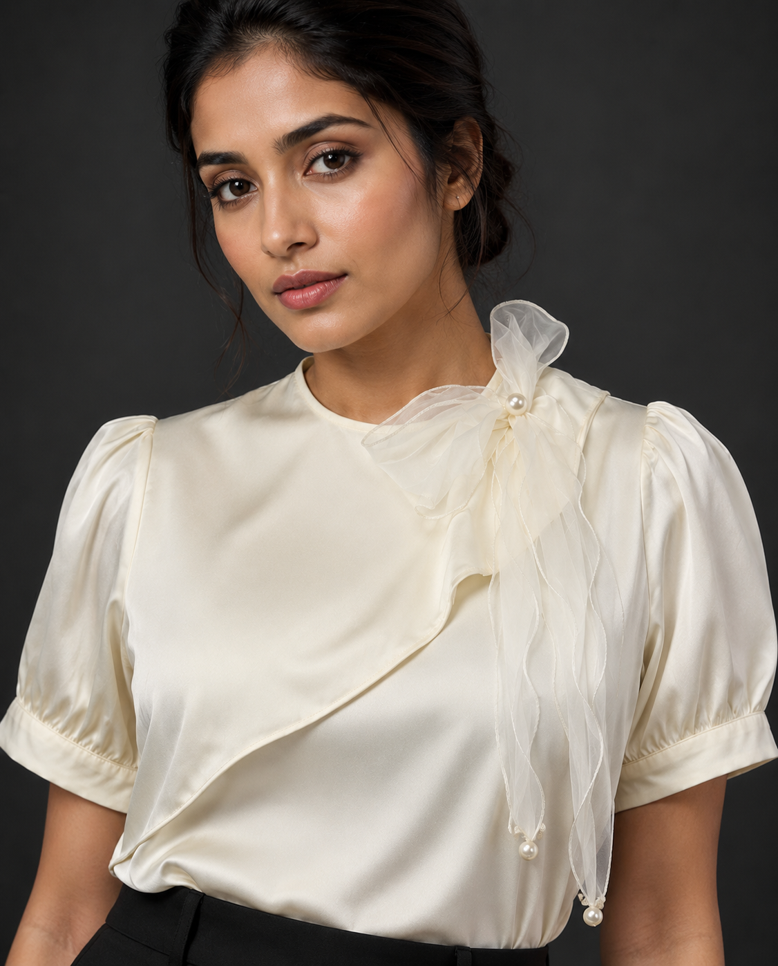Woman wearing a cream blouse with ruffled sleeves against a dark background