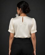 Woman wearing a white blouse with puffed sleeves against a dark background