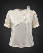 White blouse with sheer sleeves and a matching shrug on a dark background