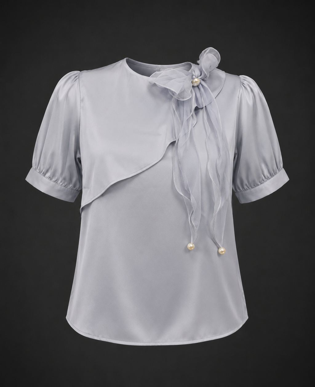 Light gray blouse with ruffled details and a bow on a black background