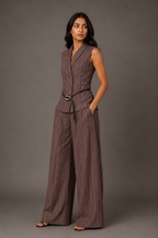 Woman wearing a brown pinstripe jumpsuit against a gray background