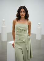 Woman wearing a strapless green dress standing against a plain background