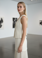 Woman in a white sleeveless top and skirt standing in an art gallery.