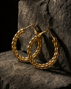 Gold hoop earrings on a textured stone surface