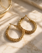 Gold hoop earrings on a marble surface