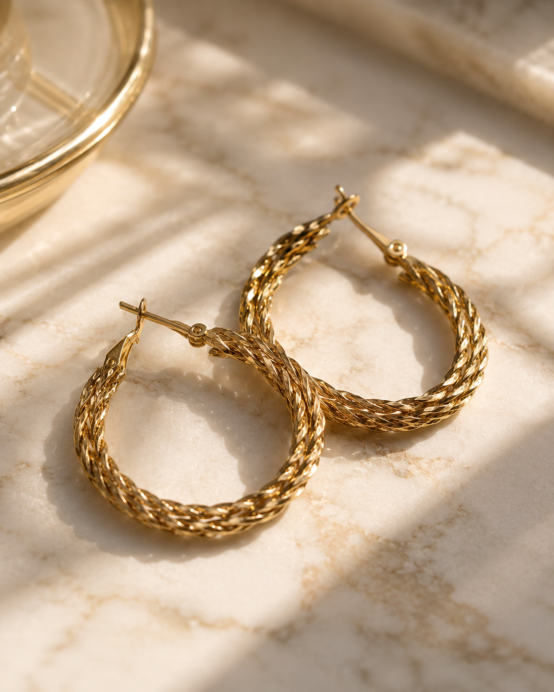 Gold hoop earrings on a marble surface