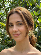 Woman with a neutral expression in front of green foliage