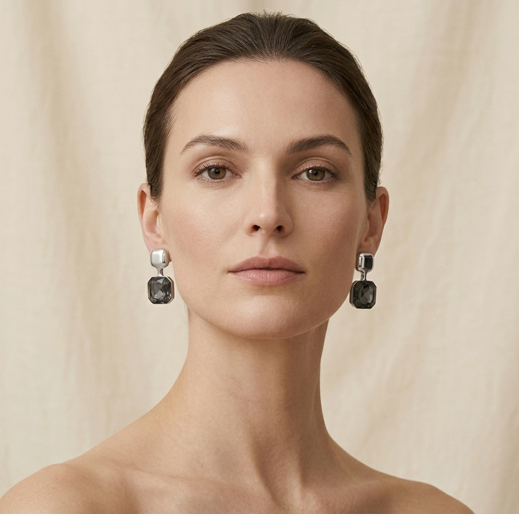 Woman wearing black drop earrings against a beige background