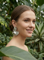 Woman wearing silver leaf earrings with a green leafy background