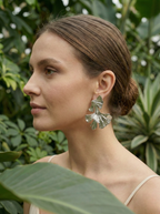 Woman wearing silver leaf earrings with a green foliage background