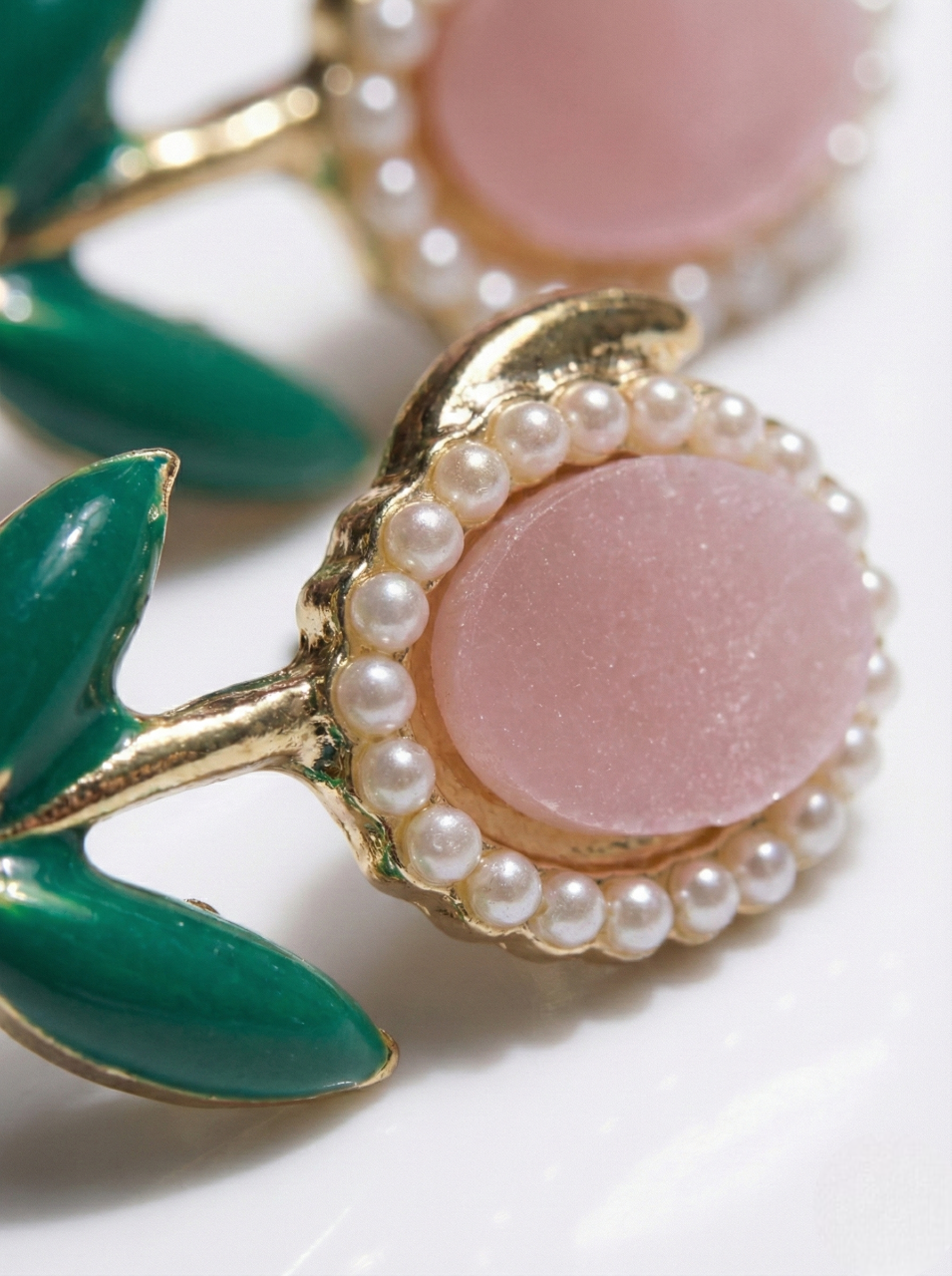 Close-up of a decorative item with pink center, green leaves, and gold frame on a white background