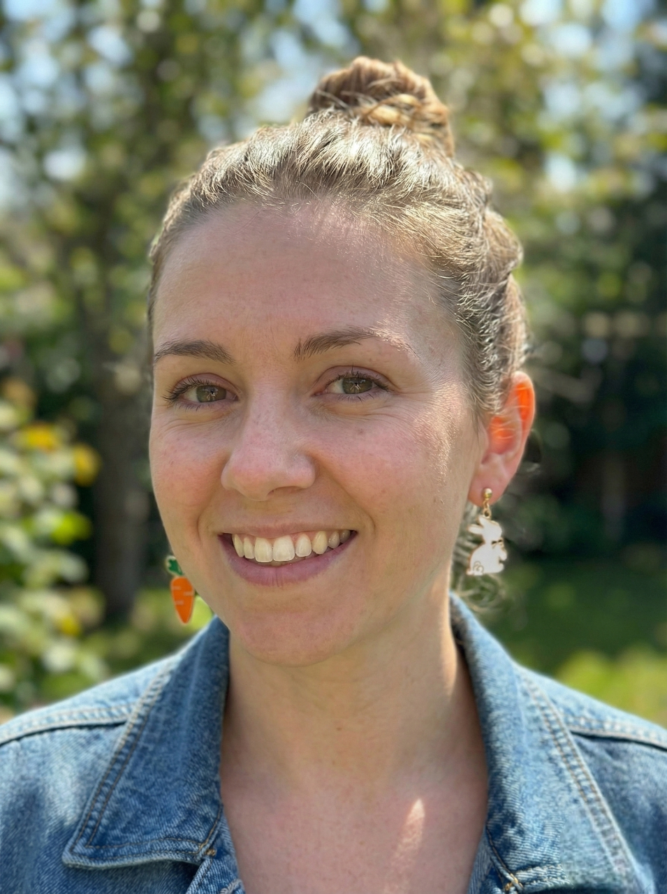 Woman with a bun hairstyle wearing a denim jacket outdoors