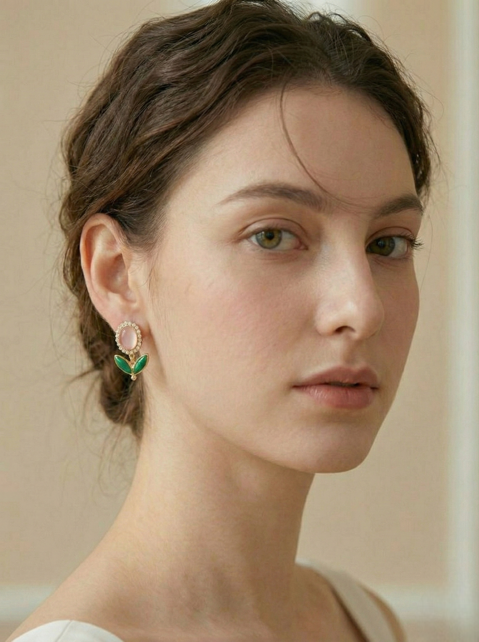 Woman wearing a pair of earrings with a neutral background