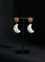 Pair of earrings on a black stand against a dark background