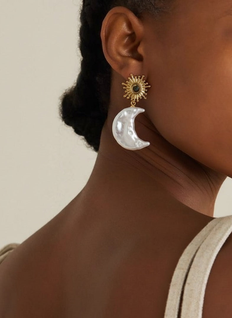 Close-up of a person wearing gold and silver earrings against a neutral background