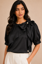 Woman wearing a black blouse with pearl details on a beige background