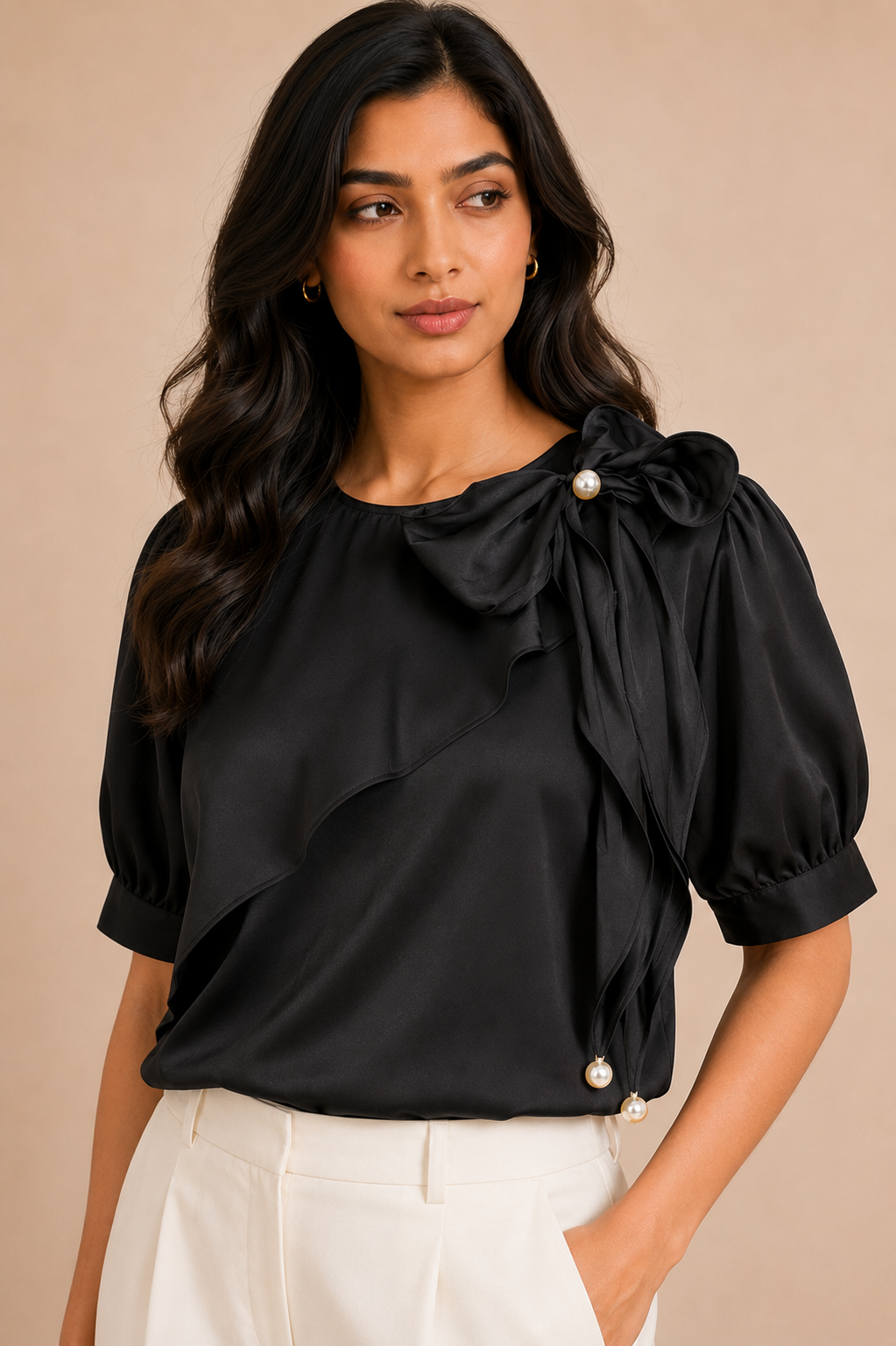 Woman wearing a black blouse with pearl details on a beige background