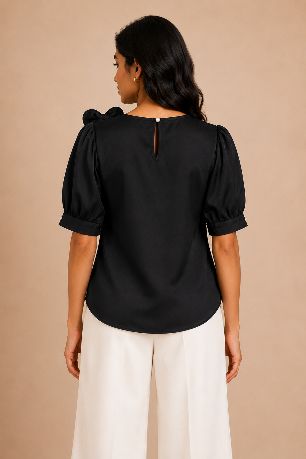Woman wearing a black blouse with puff sleeves against a beige background