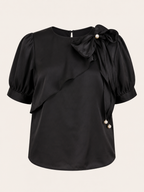 Black blouse with puff sleeves and pearl details on a beige background